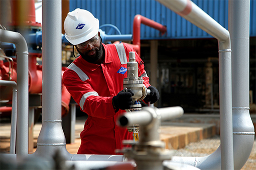 Worker in safety clothing and hard hat working on a pipe